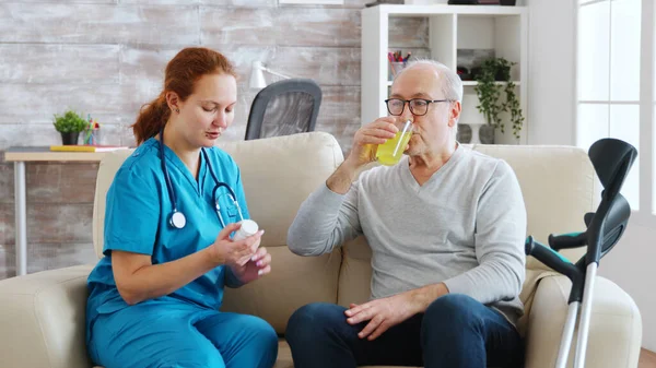 У пенсійному домі медсестра дає щоденні таблетки старій людині — стокове фото