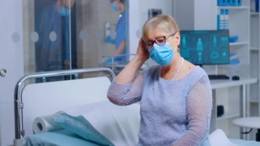 Doktorda maske takan emekli yaşlı kadın.