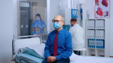 Doktor randevusunda maske takan yaşlı adam.