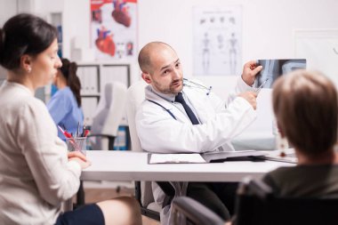 Doktor, dizindeki yaralanmayı röntgene işaret ediyor.