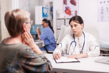 Genç doktor kıdemli hastayı muayene ediyor.
