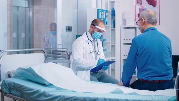 Doktor v masce mluví se starším pacientem — Stock video