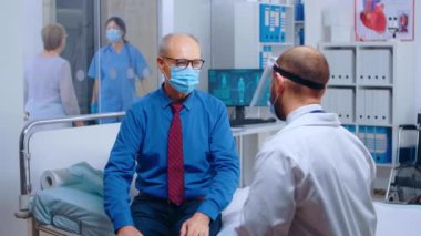 Doktor randevusunda maske takan kıdemli hasta.