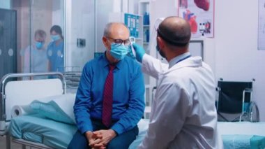 Doktor kızılötesi termometre kullanıyor.
