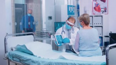 Koruyucu vizördeki doktor hastayla konuşuyor.