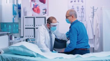 Kıdemli hastanın kalbini dinleyen bir doktor.
