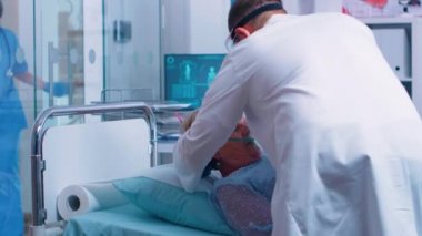 Doktor yaşlı hastaya oksijen maskesi takıyor.