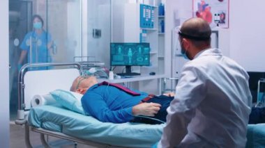 Doktor oksijen maskeli bir hastayla konuşuyor.