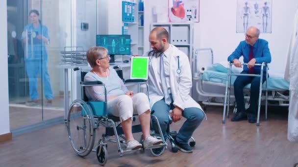 リハビリテーションセンターで緑の画面のタブレットを持つ医師 — ストック動画