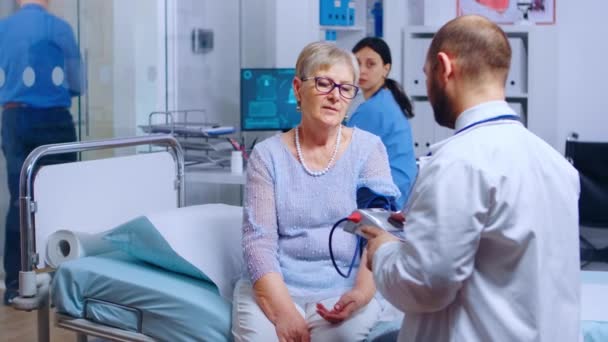 Praktyk mierzy ciśnienie tętnicze krwi emerytki — Wideo stockowe