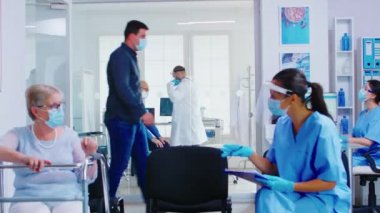Muayene odasında steteskopla yaşlı hastaların ciğerlerini dinleyen bir doktor var.