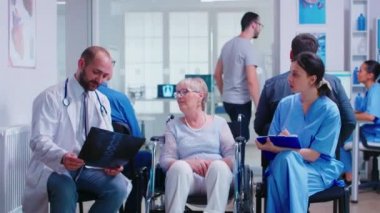 Doktor tekerlekli sandalyedeki engelli yaşlı kadının radyografisini tutuyor.
