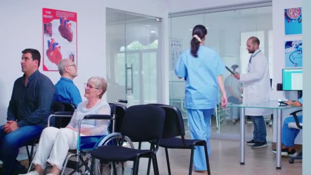 Lekarz wyjaśniający diagnozę pielęgniarce w poczekalni — Wideo stockowe