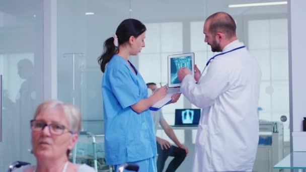 Pessoal médico segurando tablet pc com radiografia do paciente no corredor do hospital — Vídeo de Stock