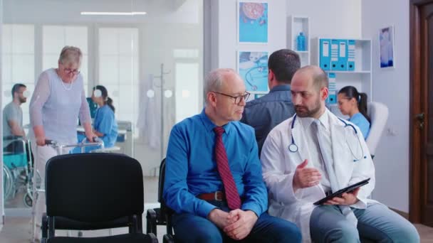 Az orvos elmagyarázza a teszteredményeket az időseknek a kórházi váróban. — Stock videók