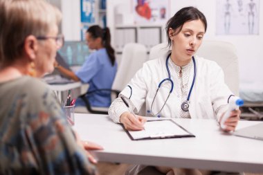 Genç doktor hasta sıcaklığı yazıyor.