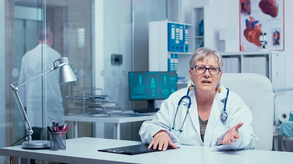 Автентична досвідчена стара жінка лікар розмовляє з камерою — стокове фото