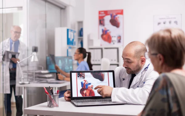 Young doctor pointing at heart on laptop screen — Stock Photo, Image
