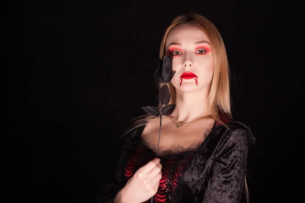 Schöne blonde Vampirfrau mit einer Rose — Stockfoto