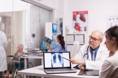 Kıdemli doktor sağlıklı akciğerlerin röntgenini işaret ediyor.