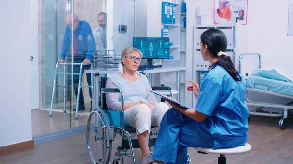 Krankenschwester spricht mit Seniorin im Rollstuhl — Stockfoto