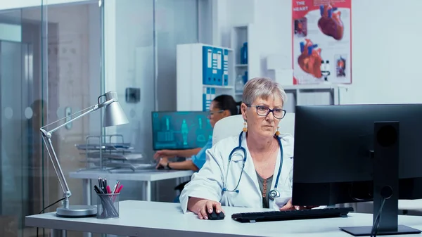 Doświadczona starsza pani doktor pracująca na PC — Zdjęcie stockowe