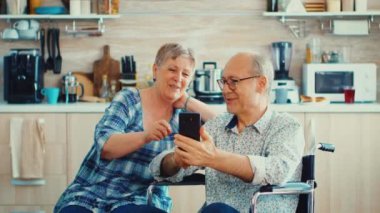 Gülümseyen engelli adam ve karısı akıllı telefon kullanıyor.