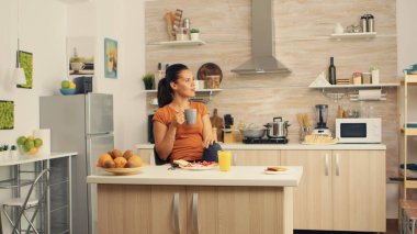 Rahatlıyor ve kahve içiyor.