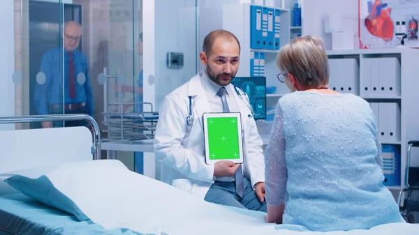 Medico con tablet schermo verde di fronte a pazienti anziani — Foto Stock