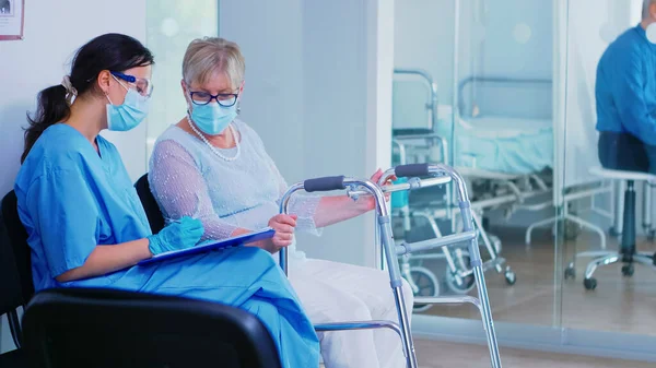 Assistente medico che compila i documenti per il paziente anziano — Foto Stock