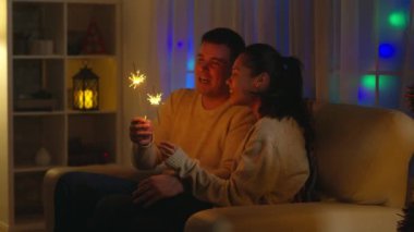 Romantik genç çift ellerinde havai fişekler tutuyor.