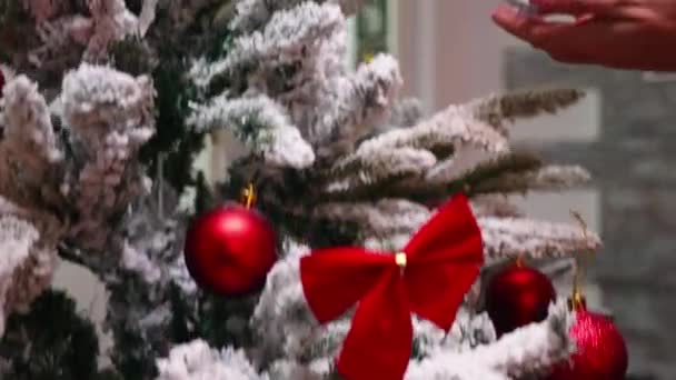 Genç bir kadın oturma odasında Noel ağacı süslüyor. — Stok video