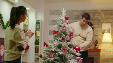 Genç adam ve kadın Noel ağacını süslüyor.