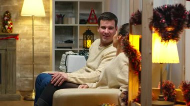 Romantik genç çift Noel günü kanepede oturuyor.