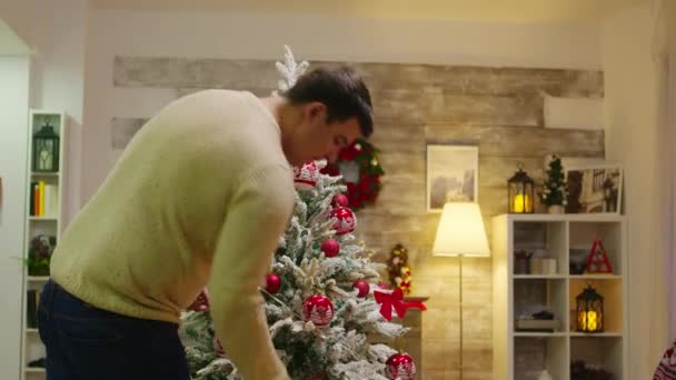 Paar mit passender Kleidung schmückt Weihnachtsbaum — Stockvideo