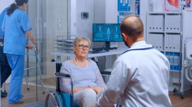 Doktor randevusunda tekerlekli sandalyedeki yaşlı kadın.
