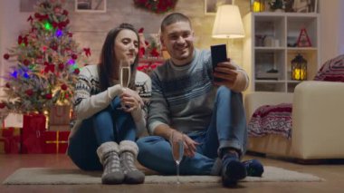 Neşeli çift bir video görüşmesi yaparken şampanya içiyor.