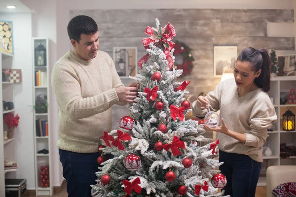 Όμορφος νεαρός και η κοπέλα του ετοιμάζουν το χριστουγεννιάτικο δέντρο τους. — Φωτογραφία Αρχείου