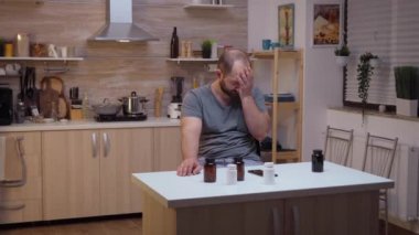 Baş ağrısı olan bir adam akıllı telefon kullanıyor.