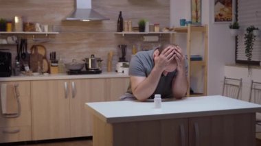 Depresyonda olan bir adam elinde bir şişe hap tutuyor.