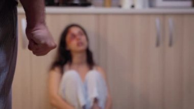 Adam karısına bakıyor ve yumruğunu sıkıyor.