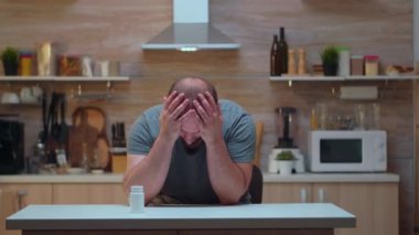 Başı ağrıyan bir koca ilaç alıyor.