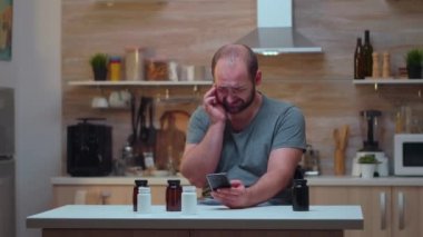 Elinde ilaç şişesi olan baş ağrısı çeken bir adam.