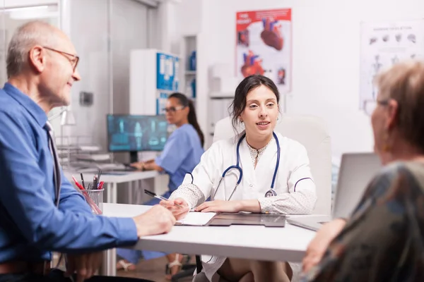 Giovane donna medico esaminando vecchia coppia — Foto Stock