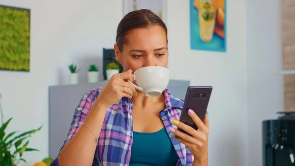 Kobieta przewijająca i pijąca herbatę — Zdjęcie stockowe