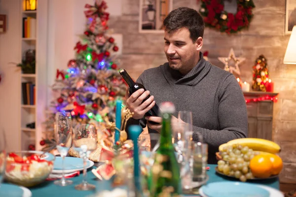 Cheerful husband looking at a bottle of wine — Stock Photo, Image