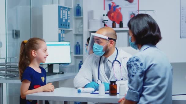 Cheerful pediatrician smiling at little girl — Stock Video