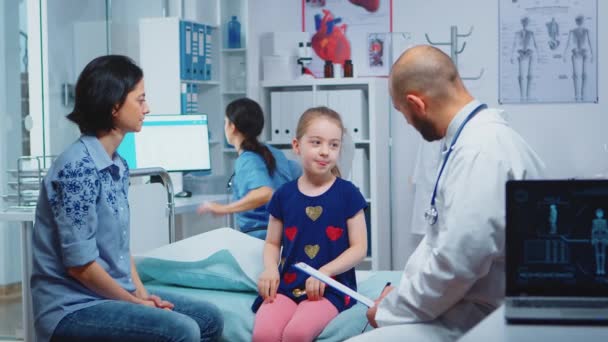 Læge taler med lille pige sidder på sengen – Stock-video