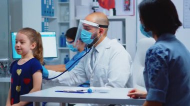 Steteskopla çocuk nefesini dinleyen doktor.