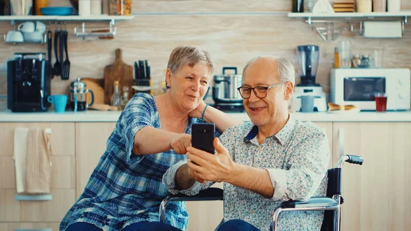 Smiling disabled man and his wife using smartphone — Stock Photo, Image